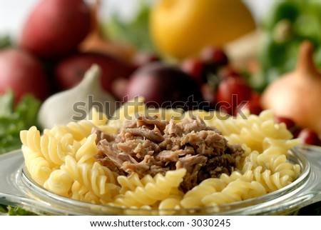 Flaked tuna on a noodle against vegetable background