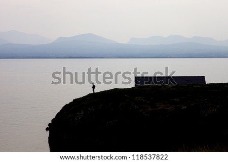 lonely man on the edge of a cliff with mountains in the background