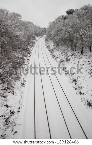 snow covered train tracks going through a forest