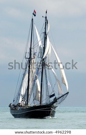 nostalgic sailboat sailing the ocean with cloudy sky background