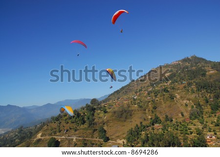 4 paragliders in nepal with clear blue sky in himalaya area