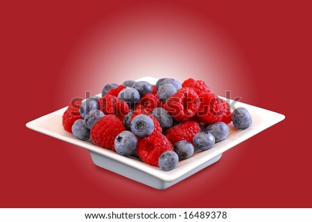 White bowl with raspberries and blueberries on a red background (easy to remove because clipping path)