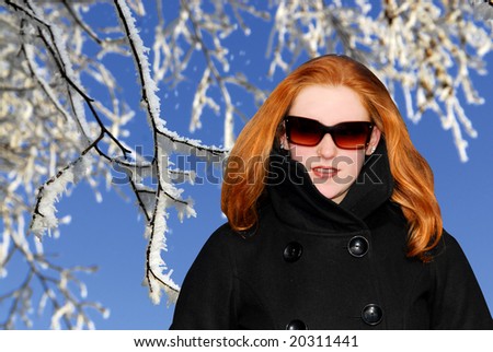 Caucasian girl with long red hair and sunglasses with white winter landscape background
