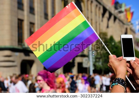 Pride flag and spectator taking pictures with mobile phone