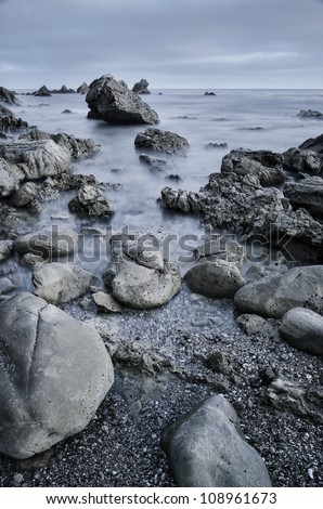 a shot of rocks on a beach in california with toned down color.
