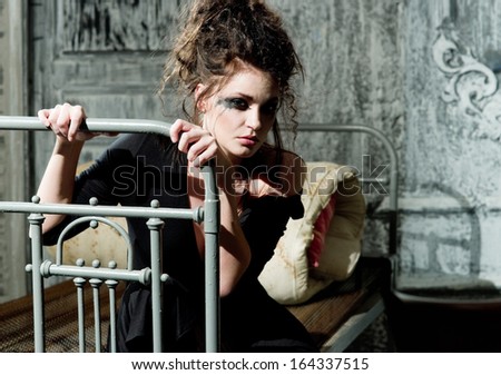 Young sad woman sitting on the old bed