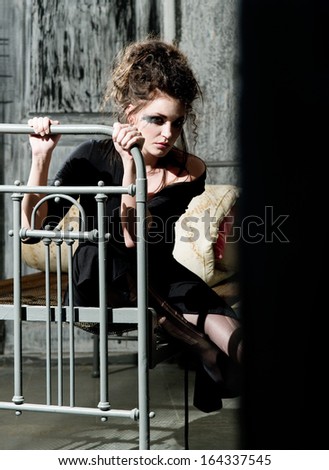 Young sad woman sitting on the old bed