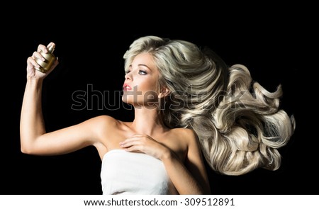 Beautiful woman with a bottle of perfume on the black background