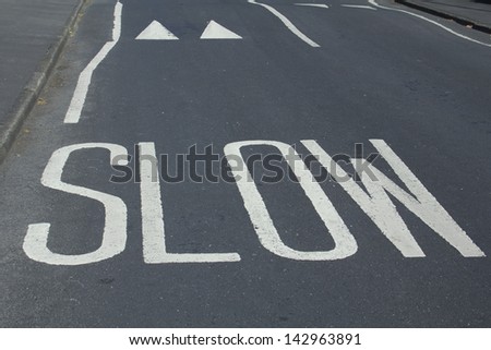 painted road warning saying \'slow\' and speed bumps