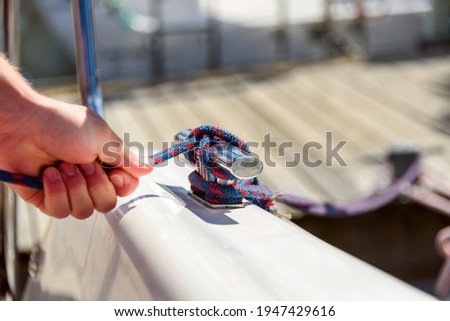 Man hand with boat rope, yachtsman tying sea knot. Human hand on sailing boat or yacht tying a knot, close up view