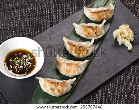 Asian appetizer menu fried dumplings with soy sauce on stone black plate