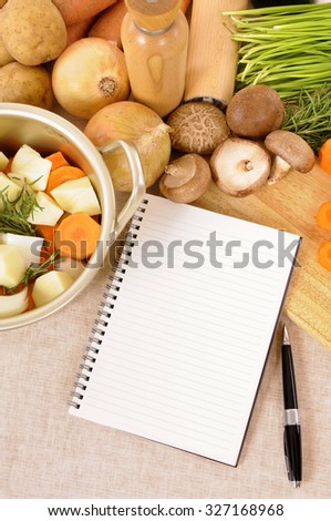 Blank recipe book or to do list on kitchen table, preparing organic winter vegetables, stock pot, vertical copy space