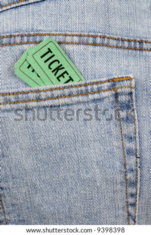 Pair of green movie or concert tickets tucked inside the rear pocket of denim jeans.