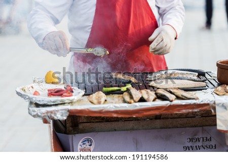 ISTANBUL - MAY 02: Turkish man sells grilled fish to tourists at Eminonu on May 02, 2014 in Istanbul. Eating on the street is a part of local life in here.
