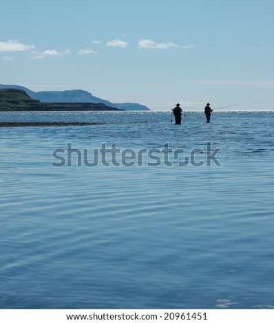 Two people fishing with rods in the sea