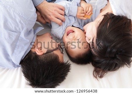 Happy family with children in bed, mother kiss her baby, asian people