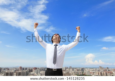 happy successful business man raised arms with cityscape and sky in the background, asian people