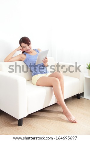 happy woman using tablet pc on sofa in the living room at home, asian beauty