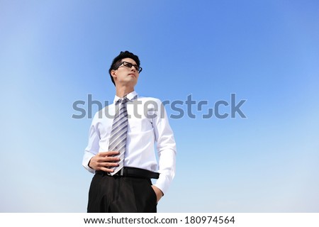 Successful handsome business man purposefully looking away with blue sky