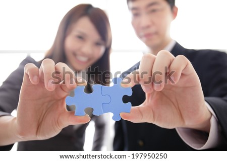 Teamwork - business people assembling jigsaw puzzle, asian
