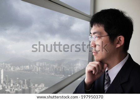 Business man look city and dark storm cloud through window with serious face, asia, hong kong, asian