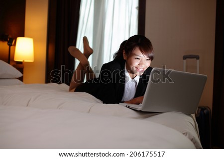 business woman working on bed with laptop in hotel at night. asian
