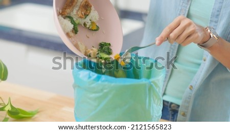 close up of asian woman scraping food leftovers or waste into kitchen bucket at home Foto d'archivio © 
