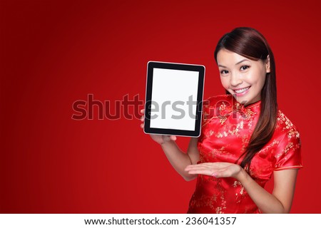 happy Chinese new year. beautiful young Asian woman holding tablet pc with empty screen isolated on red background