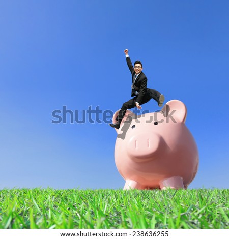 Happy Saving Money with my piggy bank - Young excited business man jump over piggy bank