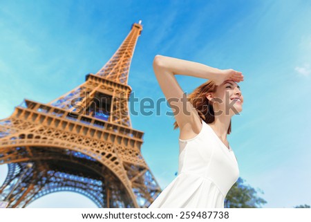 Happy woman tourist travel in Paris with eiffel tower and beautiful blue sky, she feel free and carefree. caucasian beauty
