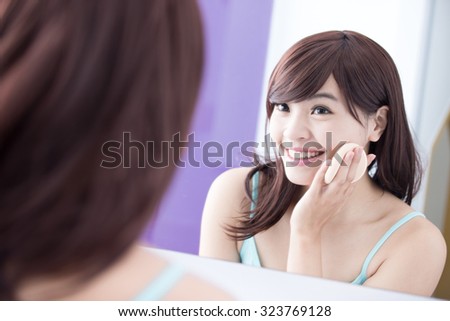 Beautiful Woman using cosmetic sponge on face with smile and look mirror. asian beauty