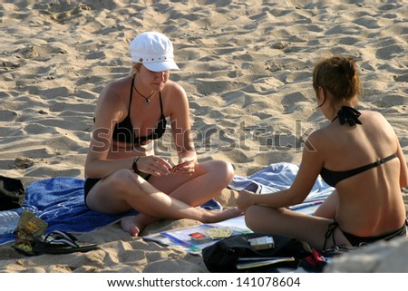 CANNES, FRANCE - JULY 24: Sunbathing and talking women at Cannes Beach on July 24, 2006 in Cannes, France. Cannes beachfront, considered between 5 best urban beach of the Europe.