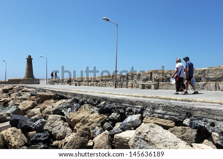 KYRENIA, NORTH CYPRUS - JUNE 17: People walking at breakwater in Kyrenia (Girne) on June 17, 2011 in Kyrenia, North Cyprus. Kyrenia harbor is currently a tourist resort.
