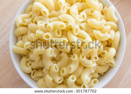 Boiled macaroni pasta in a white dishes on a wooden table