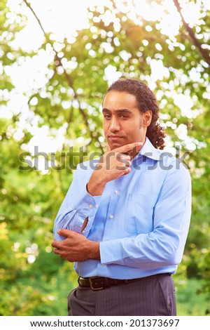 Handsome man thinking hard with green leaves on the background.
