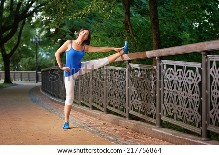 Active middle aged woman stretching in the park after running