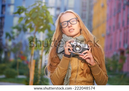 Outdoor closeup portrait of young pretty blond woman holding old fashioned vintage camera