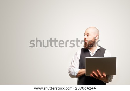 Profile portrait of bearded man in casual holding his laptop looking at copy space while standing against white background