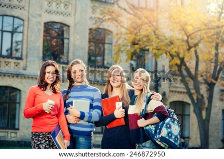 Happy student\'s life! Group of smiling young women standing together outdoors looking at camera