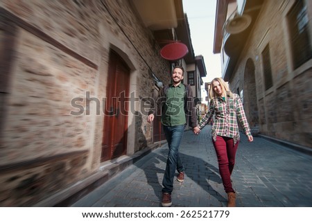 Young couple walking outdoors in old European town. Romantic happy woman and man holding hands enjoying life and romance outside. Multiracial Caucasian Arabic couple.