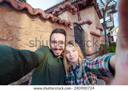 Capturing a happy moment. Beautiful young multi ethnic couple bonding to each other and smiling while making selfie with old town sightseeing in the background.