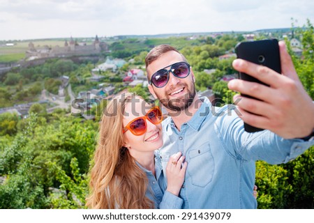 Catching the bright life moments. Beautiful young loving couple taking selfie with smart phone and smiling while traveling by Europe.