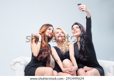 Beauty, friendship, youth and technology. Studio portrait of Three gorgeous young women taking selfie by smartphone.