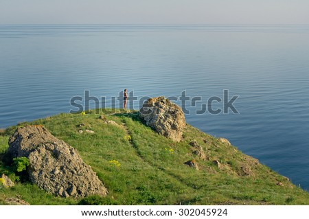 Calm and lonely. Beautiful sea view with little figure of woman on the rock.