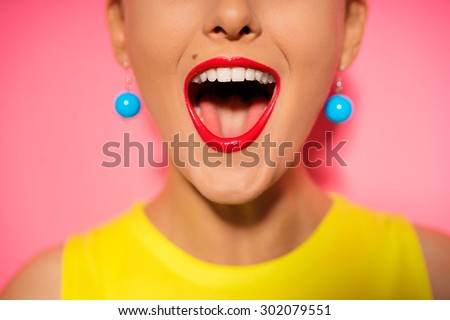 Scream and shout! Close up of opened female mouth. Bright red lips. Pink background