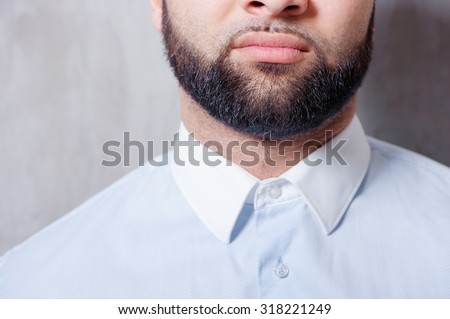Perfect beard. Close-up of young bearded man standing against grey background