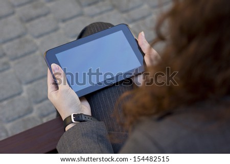Young girl dressed business suit using tablet pc. Freelance, remote work. To work on the street. The girl on the street. Digital. Business woman with computer. To sit on the bench. Tablet in hands