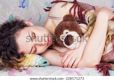 Beautiful girl sleeping soundly with curly black hair. Girl in bed canopied rug. Girl hugging a toy in sleep