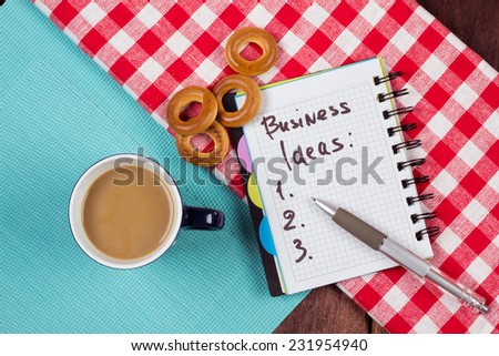 List of business ideas. Notebook for recording ideas on the table next to a cup of coffee and bagels. Brainstorming in the kitchen. The idea of undertaking business. Business idea concept. Start up.