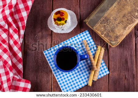 Black tea with jelly cake and a book on the table. Cozy tea party for a book at home. Book, fruit cake and black tea on a wooden table. Vintage atmosphere